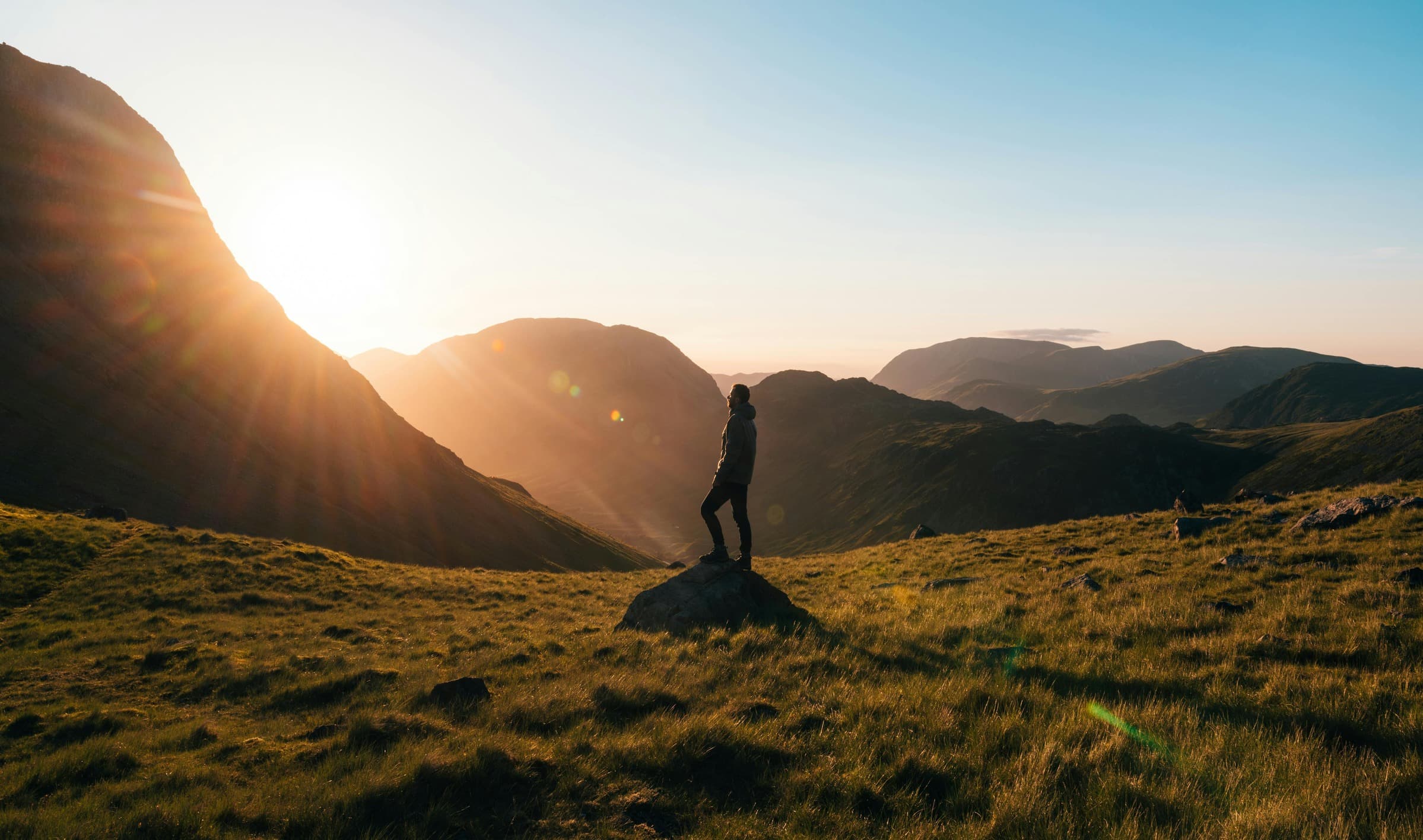 A person standing on a rock in the mountains at sunrise
